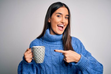 Genç, güzel esmer kadın izole edilmiş beyaz arka planda bir fincan kahve içiyor.