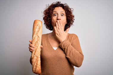 Orta yaşlı kıvırcık saçlı kadın, izole edilmiş beyaz arka planda taze ev yapımı ekmek tutuyor. Ağzı, hata yüzünden utançla kaplı, korkunun ifadesi, sessizlikten korkan, gizli bir kavram.