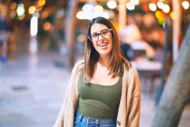 Mutlu ve kendinden emin gülümseyen genç ve güzel bir kadın. Kasaba caddesinde yüzünde gülümsemeyle dikilirken