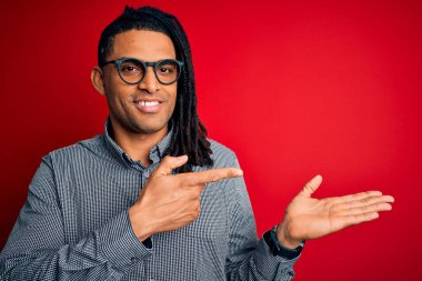 Rastgele gömlek ve gözlük takan genç, Afro-Amerikalı adam kameraya hayret ediyor ve gülümsüyor..