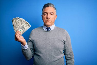 Orta yaşlı, yakışıklı, gri saçlı, mavi arka planda bir sürü dolar tutan, akıllı yüzlü, ciddi düşünen, kendine güvenen bir adam.