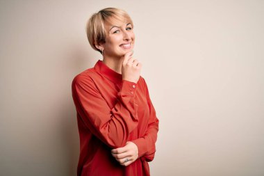 Genç, güzel iş kadını, kısa saçlı, izole edilmiş arka planda duruyor. Kameraya bakıyor, kollarını kavuşturup gülümsüyor ve çenesini kaldırıyor. Olumlu düşünüyorum..