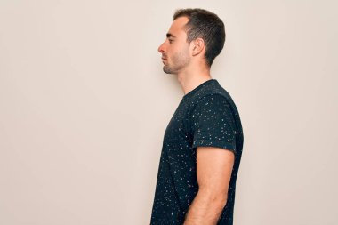 Mavi gözlü, sıradan tişörtler giyen, beyaz arka planda durup yan yan yan bakan, rahat bir görünüm takınan, kendine güvenen bir gülümsemesi olan genç, yakışıklı bir adam..