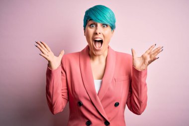 Pembe arka planda mavi saçlı genç ve güzel bir iş kadını çılgın kutlamalar yapıyor ve kollarını kaldırıp heyecanla haykırarak başarıyı kutluyor. Kazanan konsept