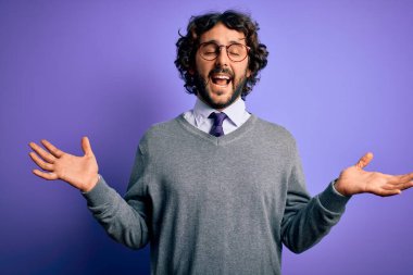 Kravat ve gözlük takan yakışıklı iş adamı. Mor arka planda duruyor. Kolları havada ve gözleri kapalı heyecanlı bir şekilde çılgın ve çılgın bir şekilde başarıyı kutluyor. Kazanan konsept