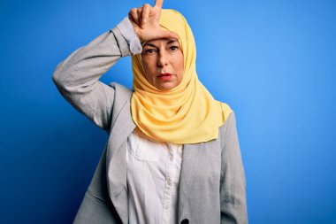 Orta yaşlı esmer iş kadını mavi arka plan üzerine geleneksel başörtüsü takıyor. Alnında parmakları olan insanlarla alay ediyor. Ezik hareketler yapıyor, alay ediyor ve hakaret ediyor..