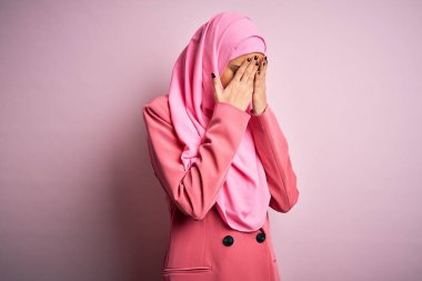 Genç, güzel, esmer, pembe Müslüman başörtüsü giyen iş kadını ve ağlarken yüzünü ellerle kapatan üzgün yüzlü iş adamı ceketi. Depresyon kavramı.