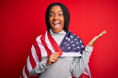 Bağımsızlık gününde Amerika Birleşik Devletleri bayrağı taşıyan genç Afro-Amerikan vatansever kadın çok mutlu ve heyecanlı, kazanan ifade zaferi büyük bir gülümsemeyle kutluyor ve ellerini kaldırıyor.