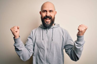 Pembe arka plan üzerinde duran sakallı yakışıklı, kel adam kollarını kaldırarak ve açık gözlerle başarıyı kutluyor ve şaşırıyor. Kazanan konsept.