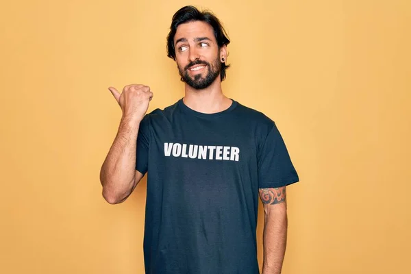 若いですハンサムなパニックボランティア男性を着てボランティアTシャツ社会的ケアとして笑顔幸せな顔を見て 親指で側面を指してアップ — ストック写真