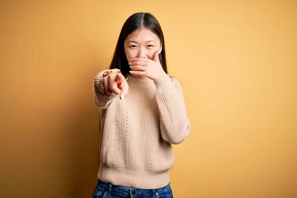 年轻美丽的亚洲女人穿着休闲装 披着黄色的孤立的背景 嘲笑你 用手指对着相机 满嘴羞愧的表情 — 图库照片