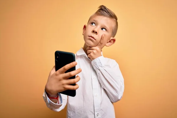 年轻的高加索小孩用智能手机 看着屏幕上的手机严肃地思考着问题 非常迷惑的想法 — 图库照片