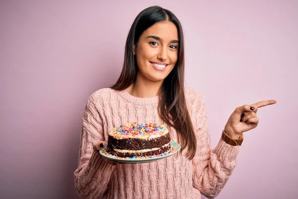 若いです美しいですブルネット女性保持誕生日おいしいケーキ以上ピンクの背景非常に幸せなポインティングとともに手と指へザ側 — ストック写真