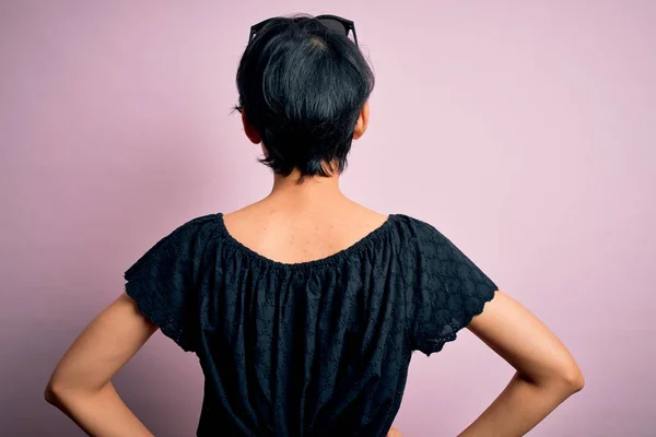 年轻美丽的亚洲女孩穿着休闲装 站在孤立的粉色背景上 背对着身体 向后看去 — 图库照片