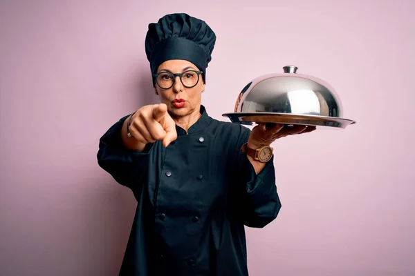 中年黑发女厨师身穿炊具制服 头戴圆顶帽 手指指向相机和你 正面积极自信的手势 — 图库照片