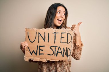 Genç, güzel, esmer bir kadın sendika bayrağı istiyor. Birliktelik mesajı taşıyor ve gülümseyen bir gülümsemeyle baş parmağıyla işaret ediyor.