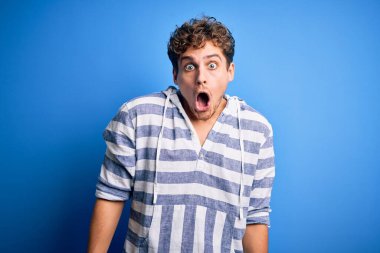 Sarışın, kıvırcık saçlı, sıradan çizgili kazak giyen, korku ve heyecan dolu bir yüz ifadesinden korkan genç, yakışıklı bir adam..