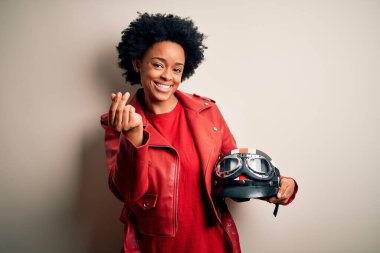 Kıvırcık saçlı, motosiklet kasklı genç Afrikalı Afrikalı motosikletçi kadın. Elleriyle para hareketi yapıyor. Maaş ödemesi istiyor.