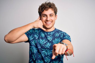 Sarışın, tatilde, kıvırcık saçlı, sıradan bir tişört giyen, gülümseyen, telefonda konuşan ve seni işaret eden genç, yakışıklı bir adam. Ara beni..