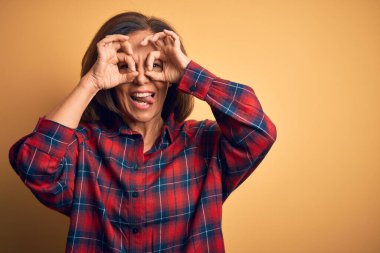 Orta yaşlı, güzel bir kadın, sarı arka planda duran sıradan bir tişört giyiyor. Dürbün gibi güzel hareketler yapıyor. Gözleri parmaklarından bakıyor. Çılgın ifade.