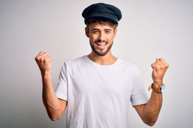 İzole edilmiş beyaz arka plan üzerinde duran sakallı genç sürücü kollarını kaldırarak ve açık gözlerle başarıyı kutluyor ve şaşırıyor. Kazanan konsept.