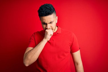 İzole edilmiş arka planda kırmızı polo giyen yakışıklı genç adam kendini iyi hissetmiyor ve soğuk algınlığı veya bronşitin belirtisi olarak öksürüyor. Sağlık hizmeti kavramı.