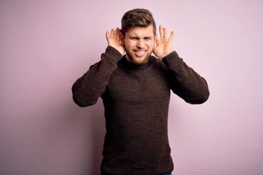 Sakallı ve mavi gözlü genç bir adam pembe arka planda sıradan bir süveter giyiyor. İki elini de kulak hareketi yaparken duymaya çalışıyor. Dedikoduya meraklı. İşitme problemi, sağır