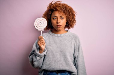 Kıvırcık saçlı, tatlı şeker yiyen, zeki yüzlü, kendine güvenen, güzel Afro-Amerikan kadın ciddi düşünüyor.