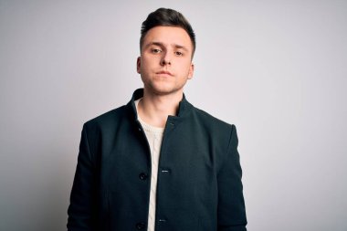 Soyutlanmış arka planda duran zarif bir kışlık ceket giyen yakışıklı genç adam yüzünde ciddi bir ifadeyle rahatladı. Basit ve doğal bir şekilde kameraya bakıyorsun..