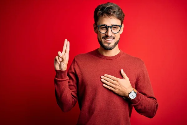 Sakallı Gözlüklü Süveterli Genç Adam Kırmızı Arka Planda Duruyor Gülümsüyor — Stok fotoğraf