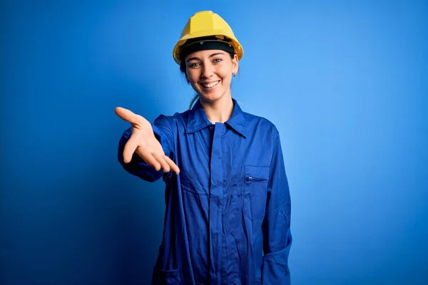 年轻美丽的女工 蓝眼睛 头戴安全帽 身穿制服 面带微笑 友善地握手致意和欢迎 成功的业务 — 图库照片