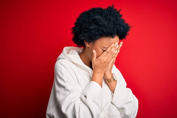 Young beautiful African American afro sportswoman with curly hair wearing sportswear with sad expression covering face with hands while crying. Depression concept.