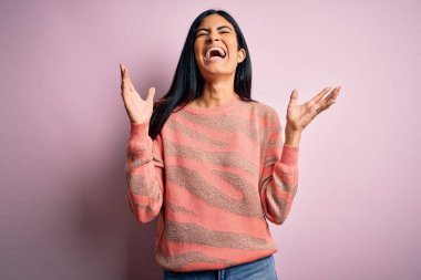 Pembe arka planda hayvan desenli süveter giyen genç ve güzel İspanyol moda kadını kollarını kaldırmış ve gözleri kapalı heyecanla haykırarak başarının çılgınlığını kutluyor. Kazanan konsept