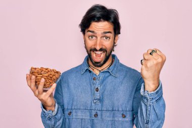 Elinde ayı olan yakışıklı İspanyol genç adam, sağlıklı bademler haykırıyor, gururla zaferi ve başarıyı kutluyor. Çok heyecanlı, coşkulu bir duygu.