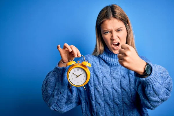 Joven Hermosa Mujer Sosteniendo Despertador Pie Sobre Fondo Azul Aislado —  Fotos de Stock