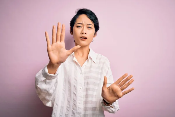 年轻美丽的亚洲女孩穿着休闲装 站在孤立的粉色背景上 用手心 愤怒和沮丧的表情做着停下来的手势 — 图库照片