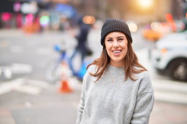 Mutlu ve kendinden emin gülümseyen genç ve güzel bir kadın. Yüzünde gülümsemeyle kentte yürürken