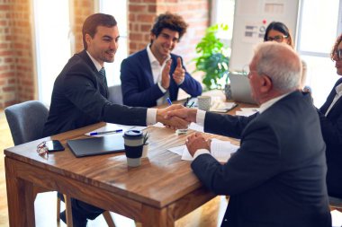 Bir grup iş adamı toplantıda mutlu ve kendinden emin gülümsüyor. Ofiste anlaşmak için el sıkışırken gülümseyerek konuşmak..