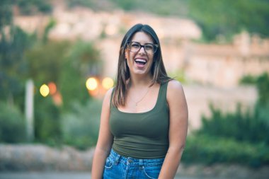 Mutlu ve kendinden emin gülümseyen genç ve güzel bir kadın. Kasaba caddesinde yüzünde gülümsemeyle dikilirken