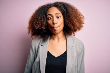 Afro saçlı, zarif ceketli, dudağıyla balık suratı yapan, çılgın ve komik bir jest yapan Afrikalı Amerikalı genç bir iş kadını. Komik ifade.