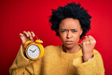 Afrika kökenli, kıvırcık saçlı, elinde klasik alarm saati olan genç bir afro kadın öfkeyle bağırıyor, çıldırıyor ve öfkeyle bağırıyor.
