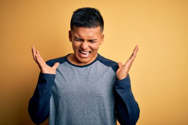 Sarı arka planda dikilen rahat tişörtlü genç, yakışıklı Latin adam kolları havada ve gözleri kapalı heyecanla haykırarak başarıyı kutluyor. Kazanan konsept