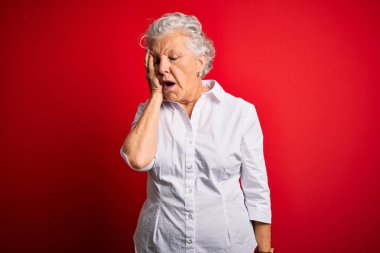 Son sınıf güzeli, zarif bir gömlek giyen, kırmızı arka planda duran, esnemekten yorgun düşmüş, yarı yüz, göz ve ağızla el ele tutuşan bir kadın. Yüzüm acıyor..