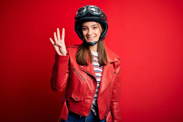 若い美しいブルネットのオートバイのヘルメットと赤いジャケットを身に着けているオートバイの女性が表示され 指番号4で指摘しながら 自信と幸せ笑顔 — ストック写真