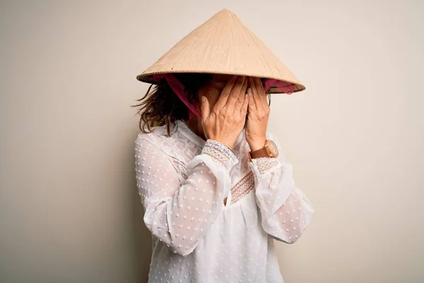 中世のブルネットの女性は泣きながら手で顔を覆う悲しい表情で白い背景にアジアの伝統的な円錐形の帽子をかぶっている うつ病の概念 — ストック写真