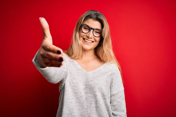 Jovem Mulher Loira Bonita Vestindo Suéter Óculos Sobre Fundo Vermelho — Fotografia de Stock