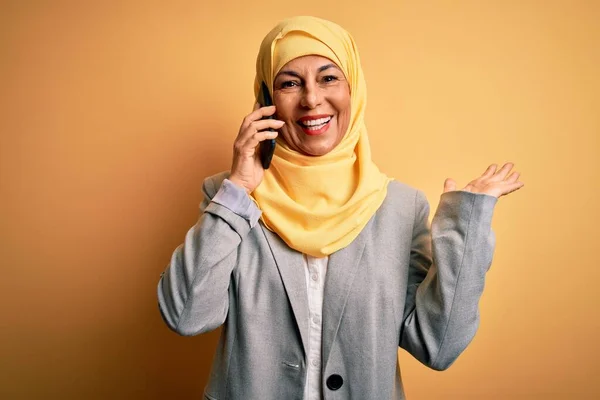 伝統的なイスラム教徒のヒジャーブを身に着けている中世の女性は スマートフォンで話す会話を持っている非常に幸せと興奮 大きな笑顔で叫んで勝利を祝う勝者式と手を上げ — ストック写真