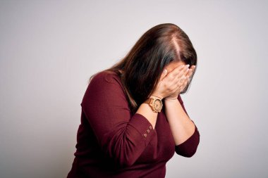 Güzel esmer ve cüsseli bir kadın izole edilmiş beyaz arka plan üzerine gündelik bir kazak giyer ve ağlarken suratını ellerle kapatır. Depresyon kavramı.