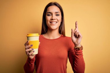 Genç güzel esmer kadın sarı arka planda bir fincan kahve içerken bir fikir ya da soru işareti ile şaşırdı.