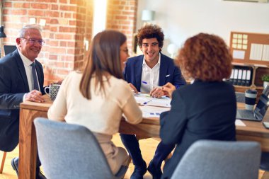 Bir grup iş adamı mutlu ve kendinden emin gülümsüyor. Ofiste birlikte çalışırken gülümseyerek konuşmak..
